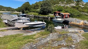 Een jachthaven met aangemeerde boten, een houten steiger en een klein rood gebouw.