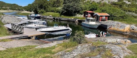 Un port de plaisance avec des bateaux amarrés, une jetée en bois et un petit bâtiment rouge.