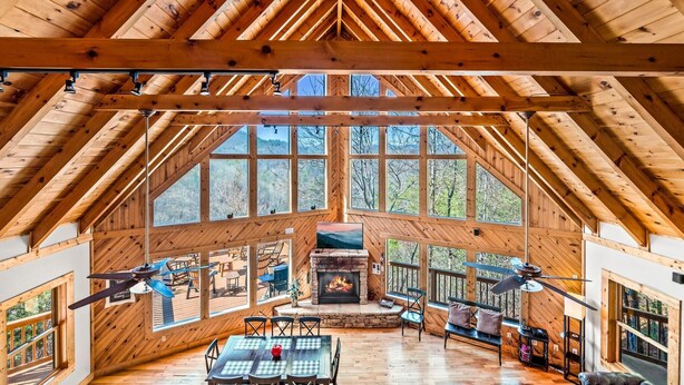 A spacious wooden interior with a fireplace, large windows, and a high ceiling. - Snail's Pace (Sevierville)