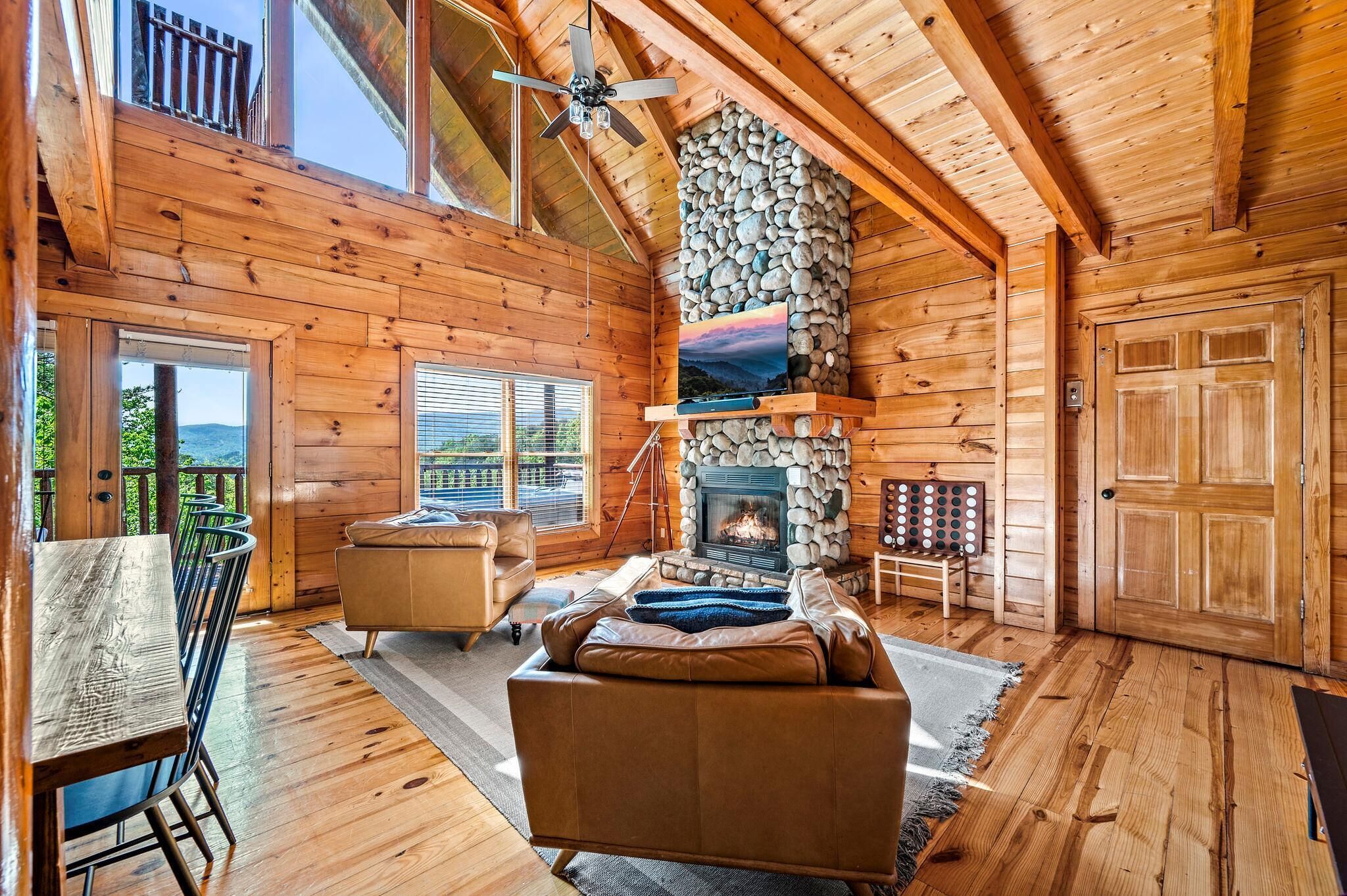 Een houten chalet van binnen met een stenen openhaard, een eethoek en een balkon.