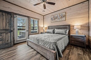 A bedroom with a bed, wooden walls, a ceiling fan, and a window with blinds. - Mountain Bliss (Sevierville)