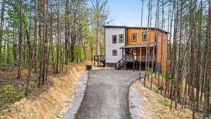 A modern two-story cabin with a concrete driveway leading to a wooden deck. - Mountain Bliss (Sevierville)