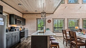 Ein Holzblockhaus-Interieur mit Küche, Essbereich und großen Fenstern.