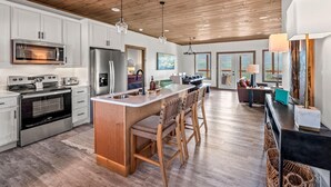 A spacious kitchen with modern appliances, a wooden ceiling, and a large island with bar stools. - Premier Mountain Views (Gatlinburg)
