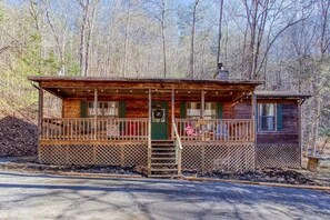A cabin with a porch, a chimney, and a small attached structure. - Sleepy Bear (Sevierville)