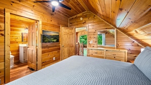 Ein Schlafzimmer einer Holzhütte mit Bett, Kommode und Deckenventilator.