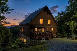 Eine Holzhütte mit Veranda, Treppe und Blick auf den umliegenden Wald.