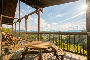 Eine Holzdar Terrasse mit Tisch und Stühlen, mit Blick auf eine gebirgige Landschaft.