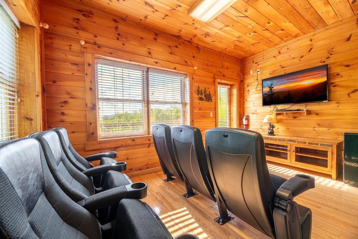 Een interieur van een blokhut met houten wanden, een televisie en een rij stoelen.