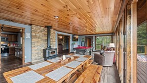Un interior de madera con mesa de billar, chimenea de piedra y comedor.