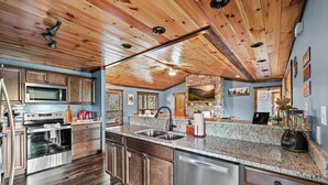 Cocina con techo de madera, encimeras de granito, electrodomésticos de acero inoxidable y salpicadero de piedra.