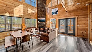 Ein Holzblockhaus-Interieur mit Kamin, Sitzecke und großen Fenstern.