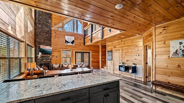 Eine geräumige Holzhütte mit großem Interieur, einem Steinkamin und einem Essbereich mit langem Tisch.