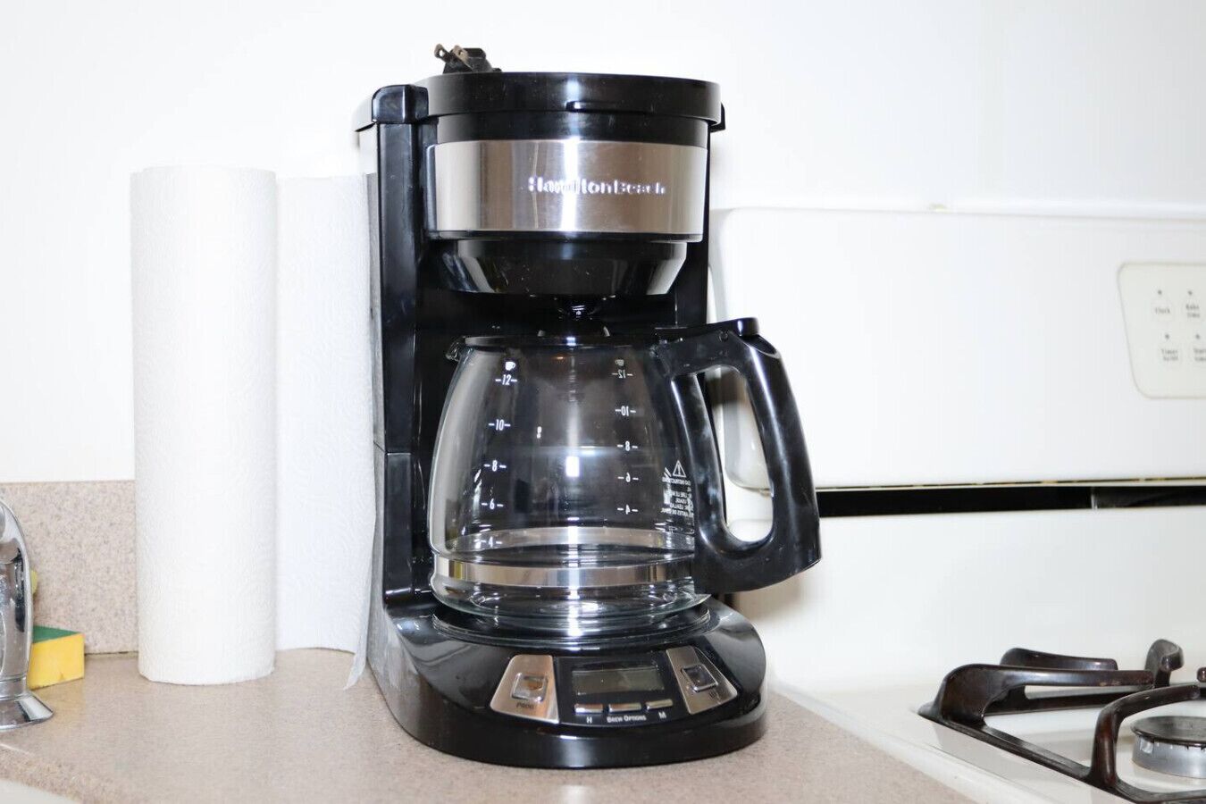 A black coffee maker with a clear carafe on a kitchen counter.