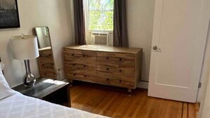 Quarto com cama, cômoda, espelho e porta.