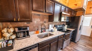 Una cocina con armarios de madera oscura, un refrigerador de acero inoxidable, una cafetera y un microondas.