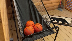 A basketball hoop with a net, three basketballs, and a bear decoration on a wooden deck. - Cozy Hollow Cabin (Sevierville)