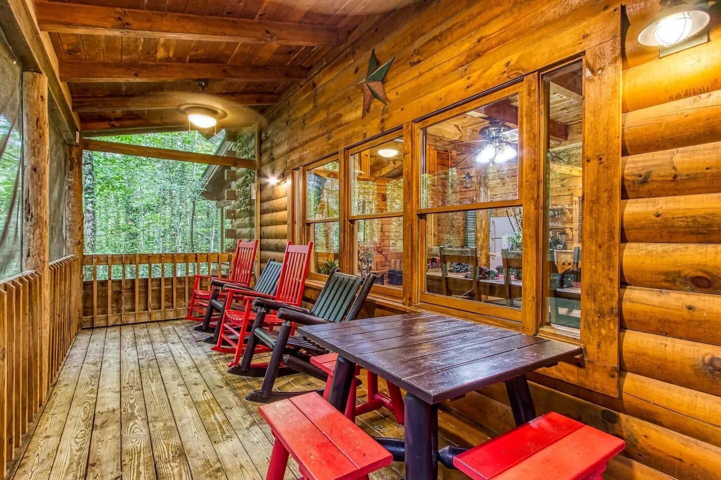 Une cabane en bois dotée d’un porche abrité, de murs en bois et de grandes fenêtres.