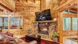 A log cabin interior with a stone fireplace, leather sofa, and large windows. - Z - Timber Wolf Unit 2 (Sevierville)
