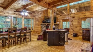 A wooden cabin interior with a dining area, kitchen, and large windows. - Z - Timber Wolf Unit 2 (Sevierville)