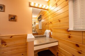 Ein Badezimmer mit Holzwandverkleidung, Waschbecken, Spiegel und Handtuchhalter.