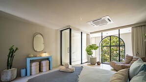 A modern bedroom with a large bed, a blue console table, a mirror, and a view through a large window.