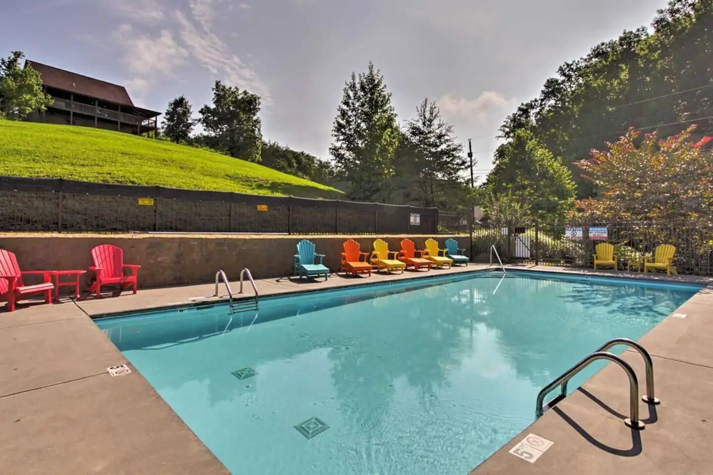 A swimming pool with a clear blue water, surrounded by a concrete deck.