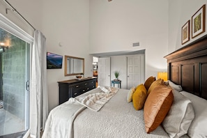 A bedroom with a bed, a dresser, a mirror, and a door leading to another room. - Gracious Oasis (Gatlinburg)