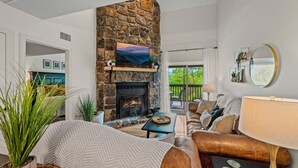 Una sala de estar con chimenea de piedra, un sofá, una mesa de centro y un televisor.