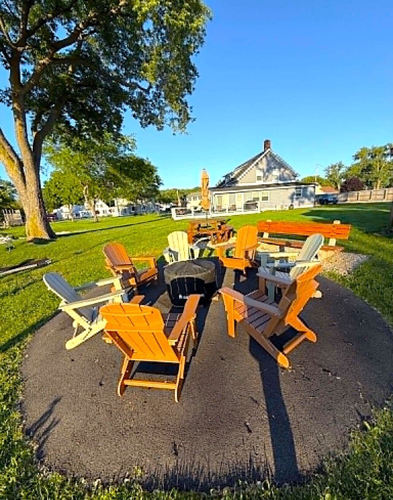 Espace extérieur aménagé avec des chaises et des tables, un arbre et un bâtiment en arrière-plan.
