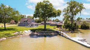 Un barrio residencial con una casa, un muelle y un pequeño bote.