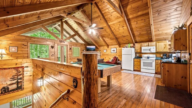 A wooden cabin interior with a pool table, kitchen area, and a large window. - Mountain Dream (Sevierville)