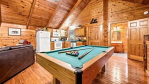 A wooden interior with a pool table, a sofa, and a kitchen area. - Mountain Dream (Sevierville)