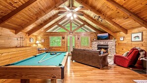 A wooden interior with a pool table, a fireplace, and a couch. - Mountain Dream (Sevierville)