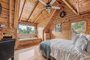 Eine Holzhütte mit einem Bett, einem Schreibtisch und einem Fenster mit Blick auf Grünflächen.