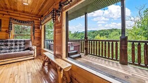 A wooden cabin with a porch, a sofa, and a bench. - Away in the Mountains (Sevierville)