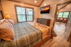 A bedroom with a bed, a dresser, a window, and a painting on the wall. - Away From It All (Sevierville)