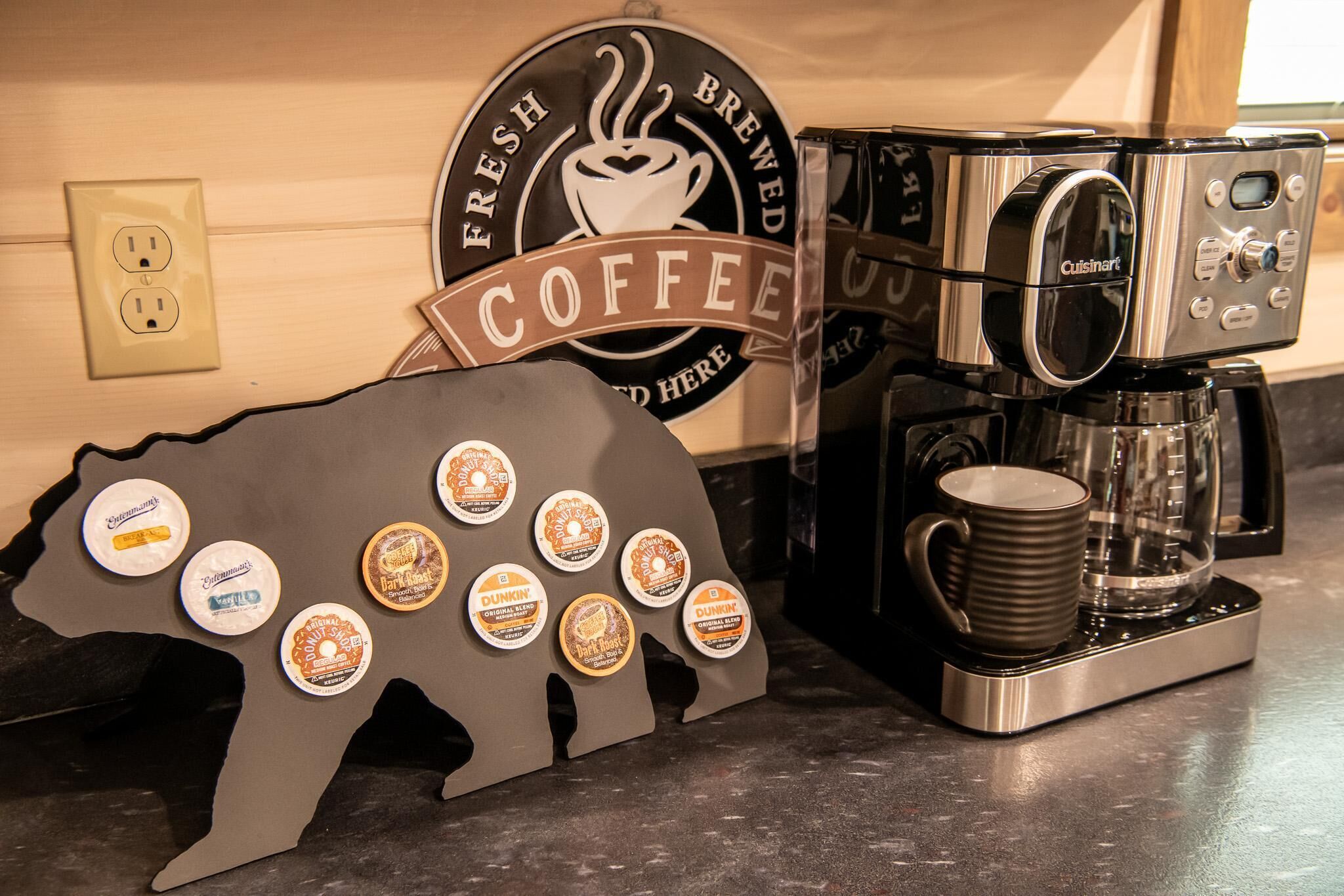 A coffee machine, a coffee cup, and a wall with a coffee shop sign.