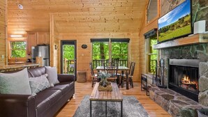 Ein Holzblockhaus-Interieur mit Kamin, Essbereich und einer Couch.