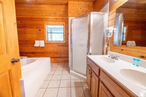 A wooden cabin bathroom with a bathtub, a shower, a sink, and a mirror. - Nicoha (Sevierville)