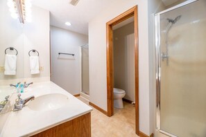 A bathroom with a sink, mirror, towel rack, shower, and toilet. - Peachtree (Sevierville)