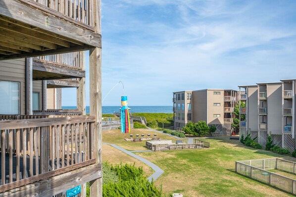 A coastal residential area with wooden balconies, a blue lighthouse, and a view of the sea. - Lovely condo with Ocean views! Great location, walk to the town of Duck (Kitty Hawk)