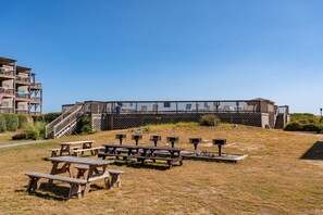 Eine Holzterrasse mit Picknicktischen, einer Treppe und einem Gebäude mit Balkonen.