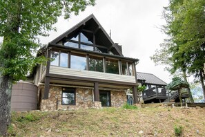 A two-story stone house with a large balcony and a wooden deck. - The Top (Sevierville)