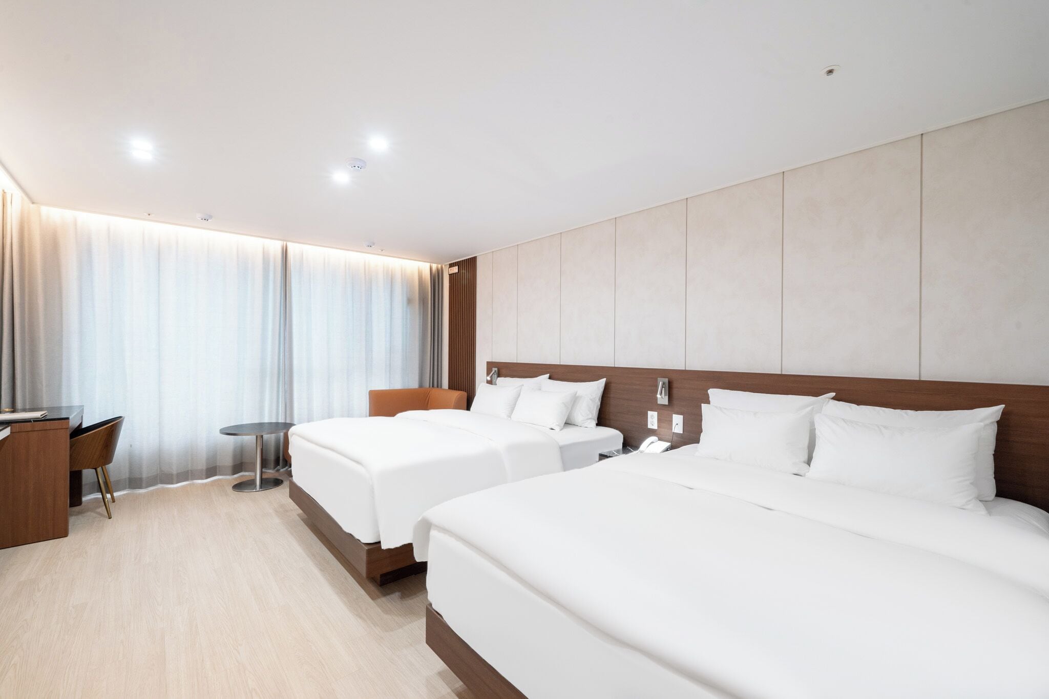 Habitación de hotel con dos camas, un escritorio y una silla.