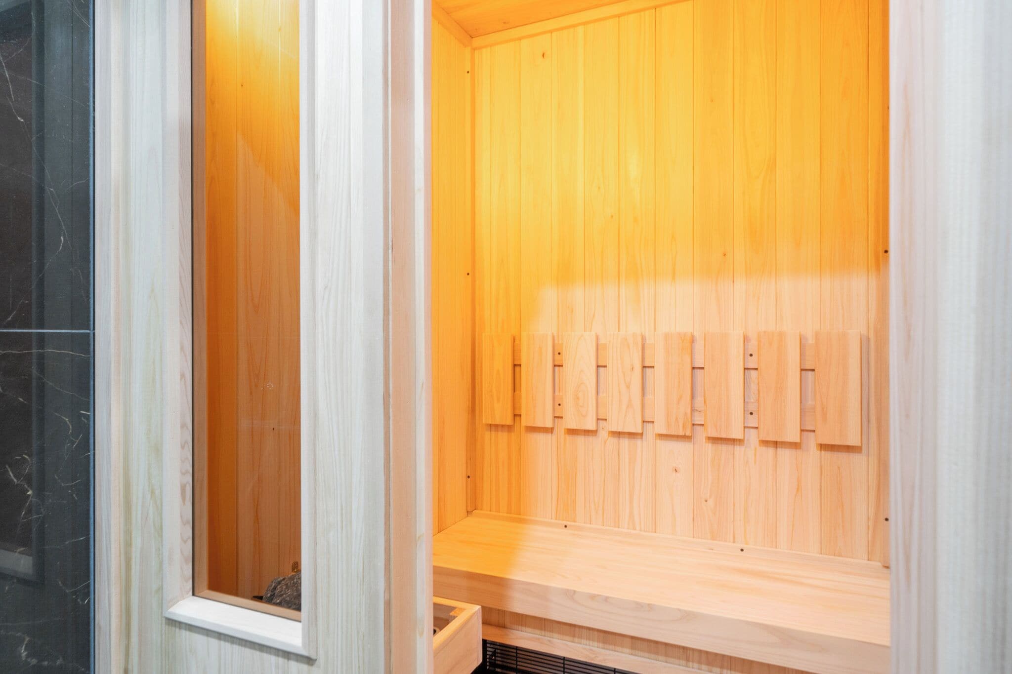A sauna with wooden benches and a glass door.