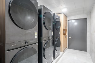 Un cuarto de lavandería con varias lavadoras, un armario de madera y una puerta cerrada.