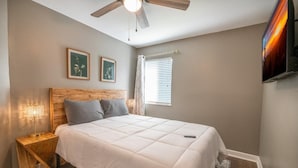 A bedroom with a bed, a wooden nightstand, a ceiling fan, a TV, and two framed pictures on the wall. - Enchanted Treehouse Hideaway (Gatlinburg)