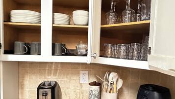 A kitchen with a granite countertop, a toaster, a coffee maker, and a black air fryer.