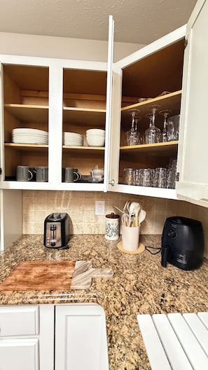 Eine Küche mit einer Granitabdeckung, einem Toaster, einer Kaffeemaschine und einem schwarzen Heißluftfritteuse.